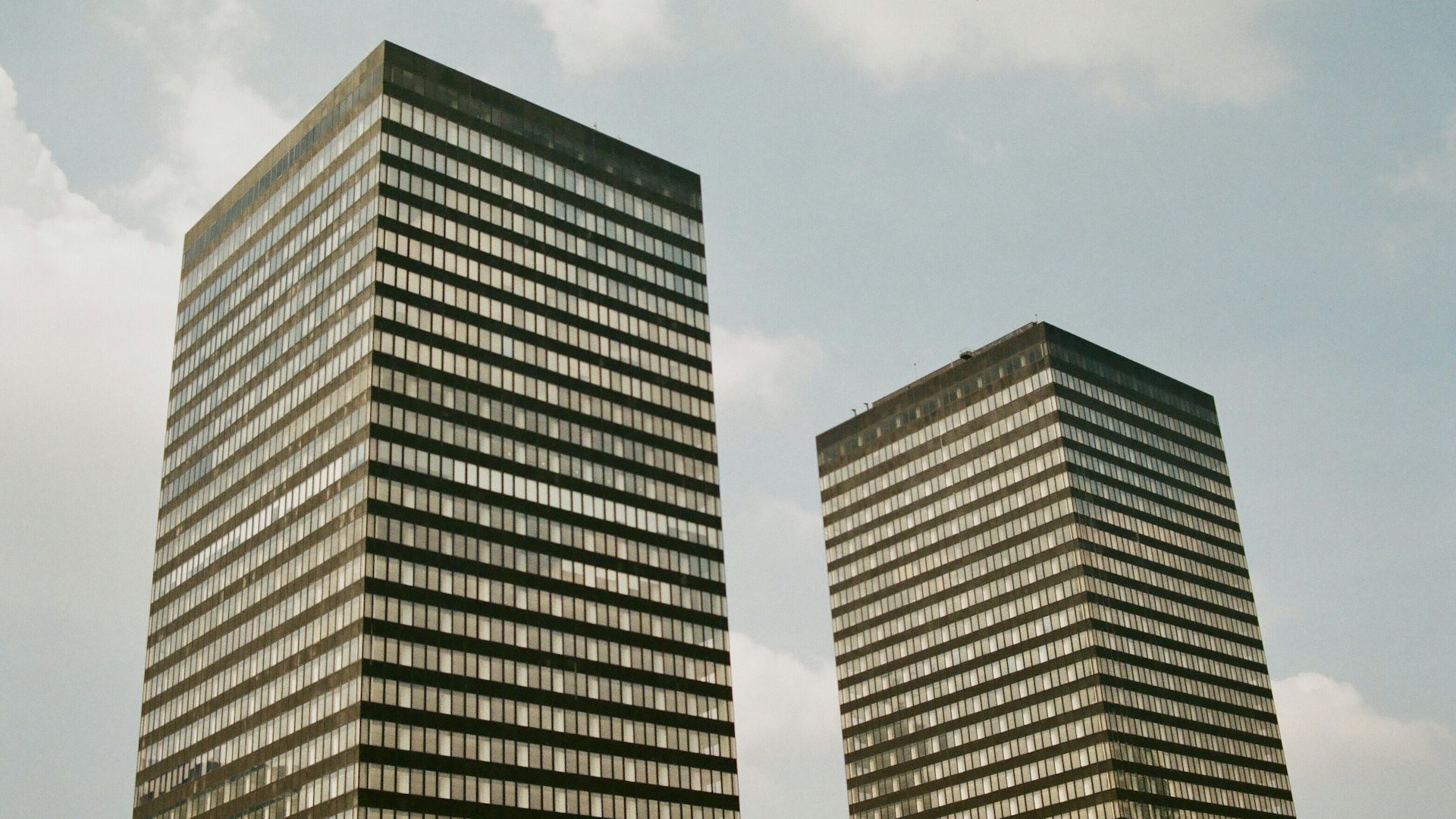Two tall office towers under a cloudy sky