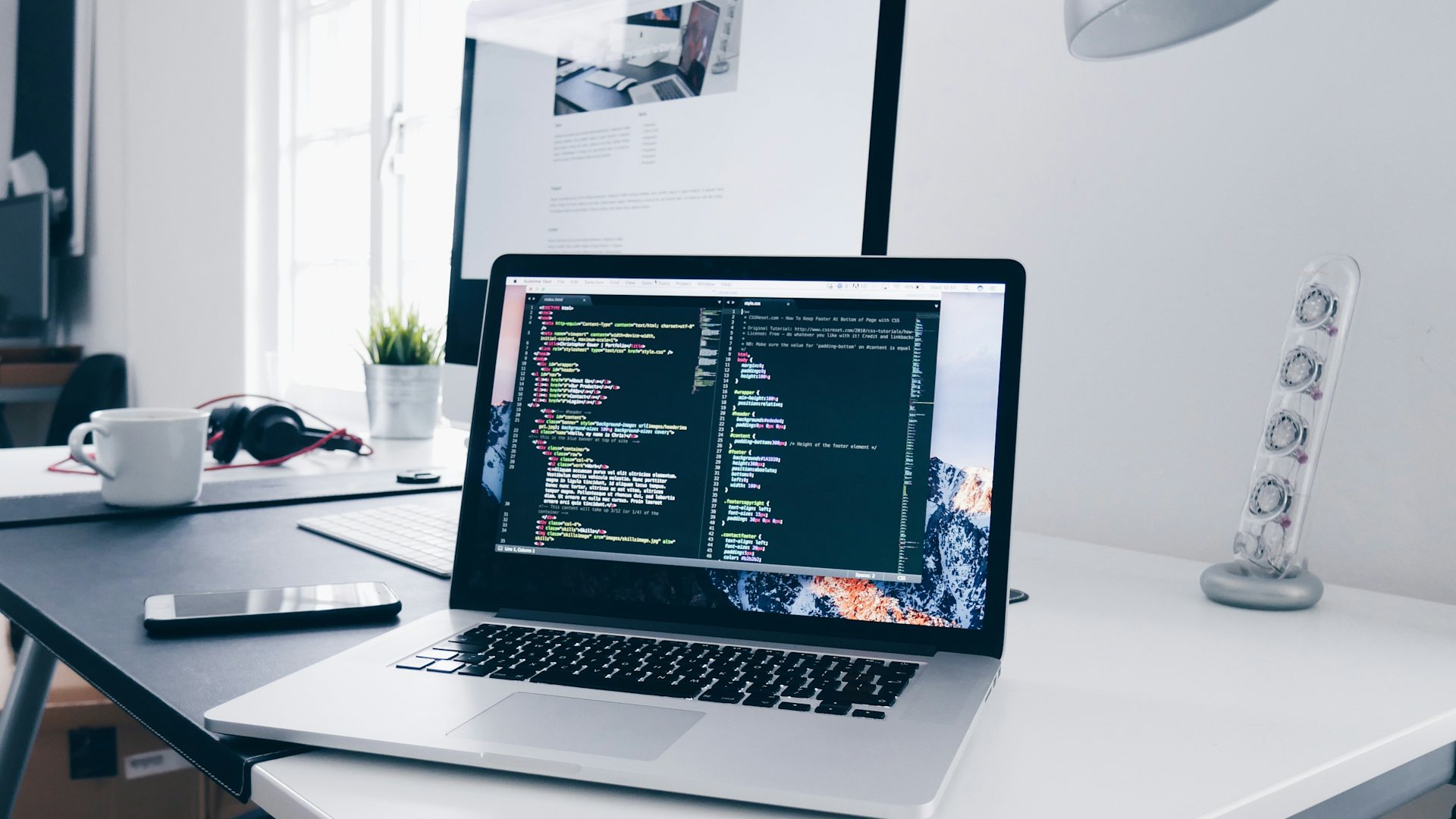 Laptop showing website code on a work desk