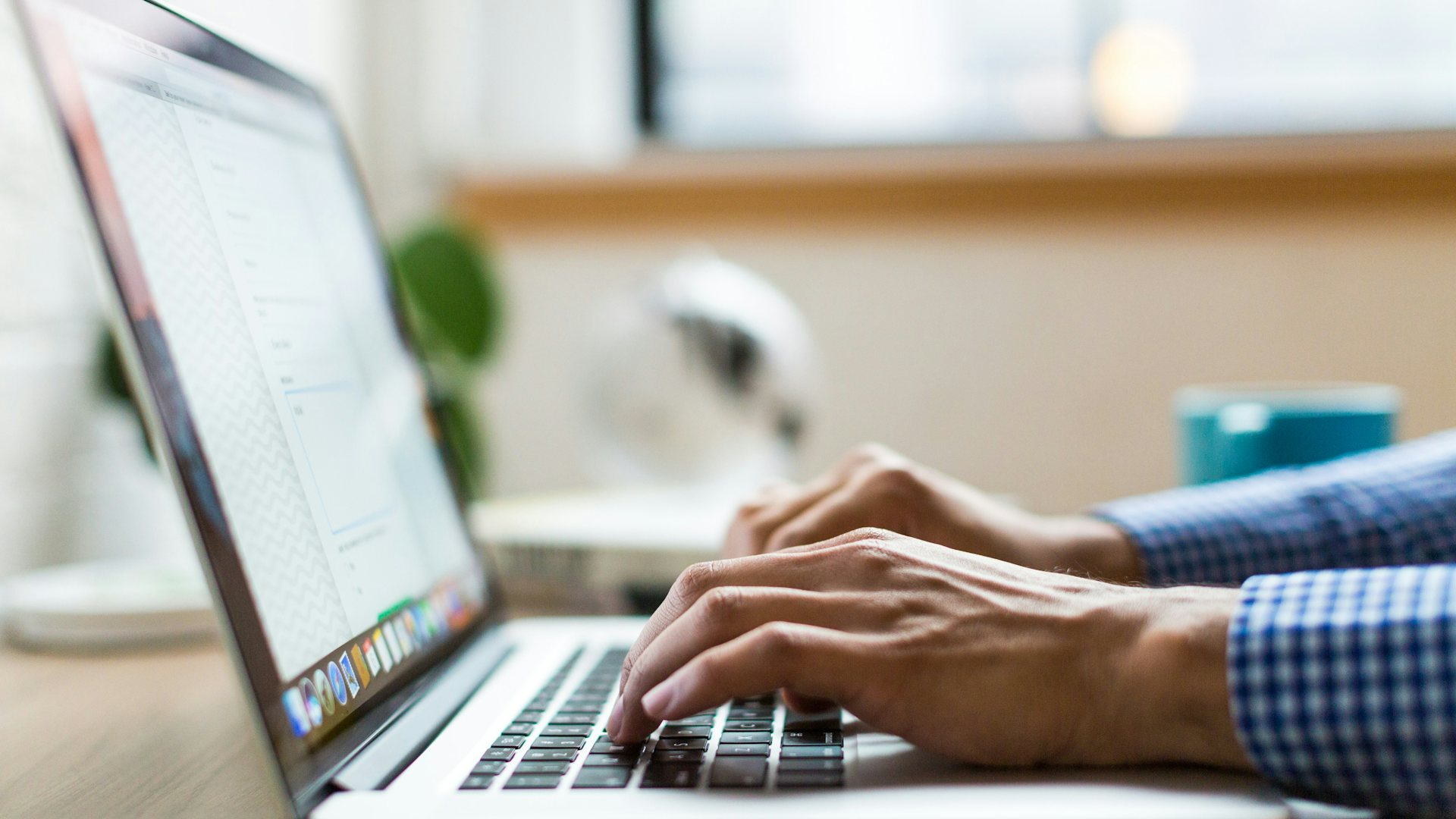 Hands typing on a laptop at an office desk