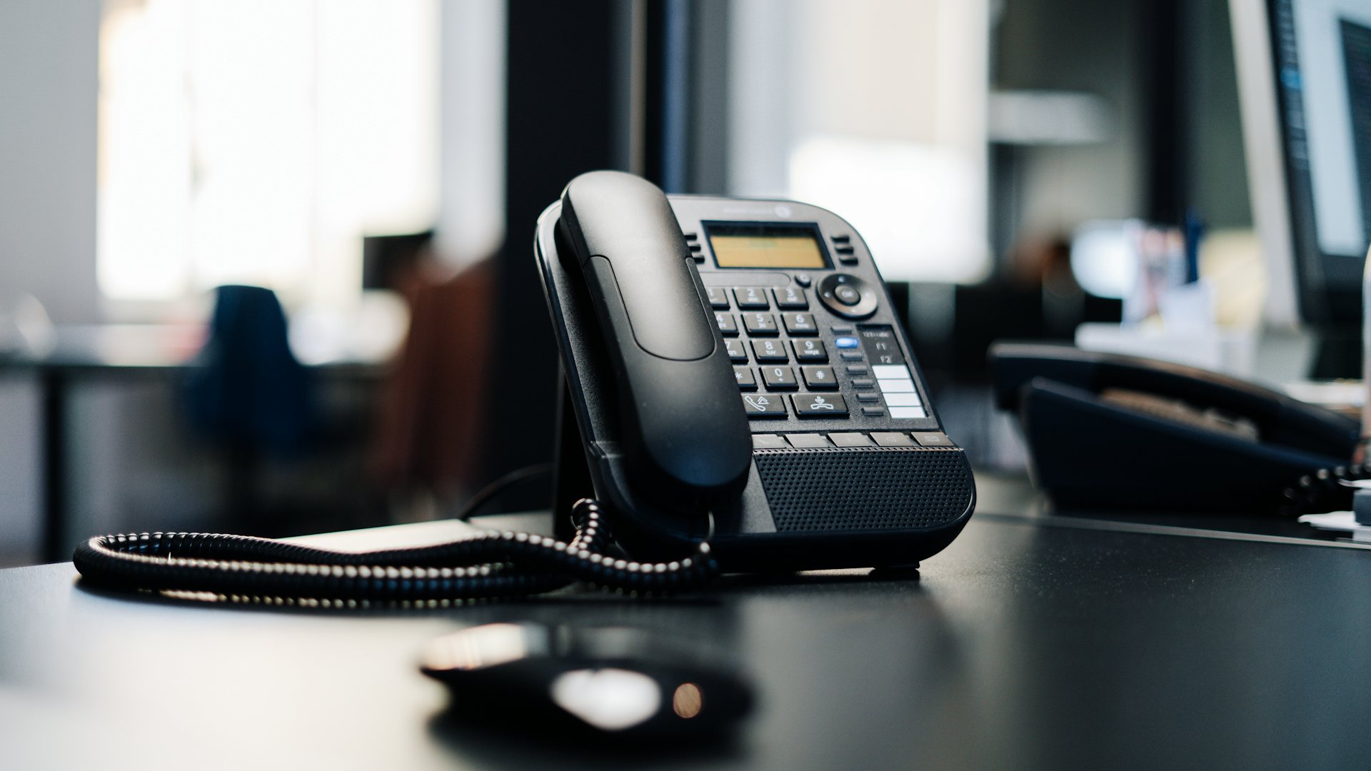 Black IP desk phone on an office desk