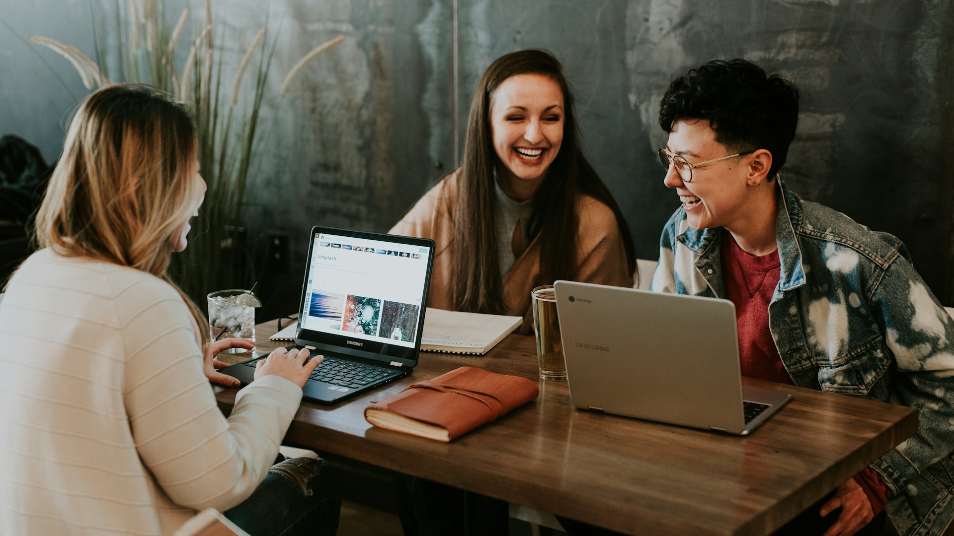 Three people working together at laptops and laughing