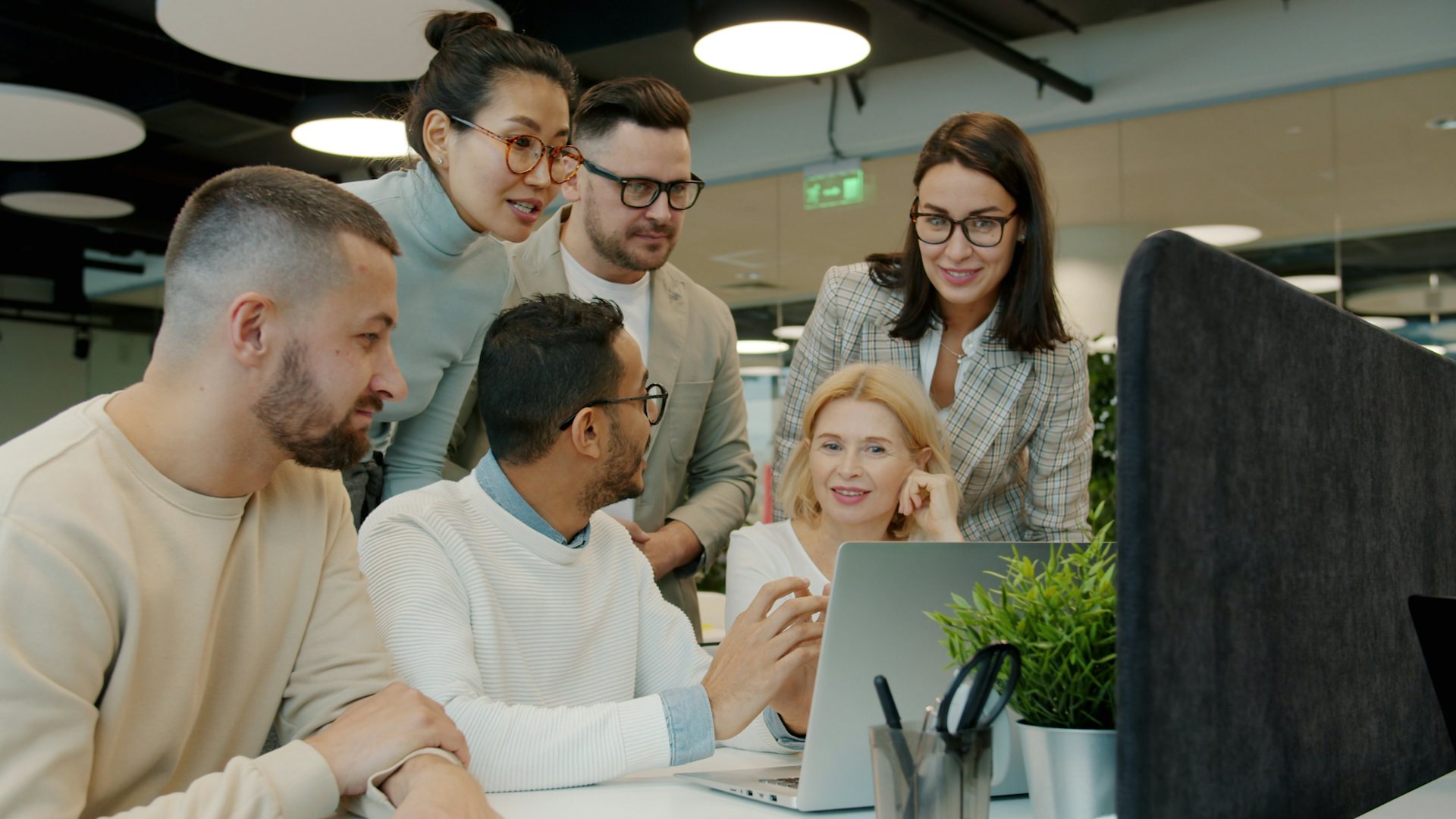 Office team discussing together around a laptop